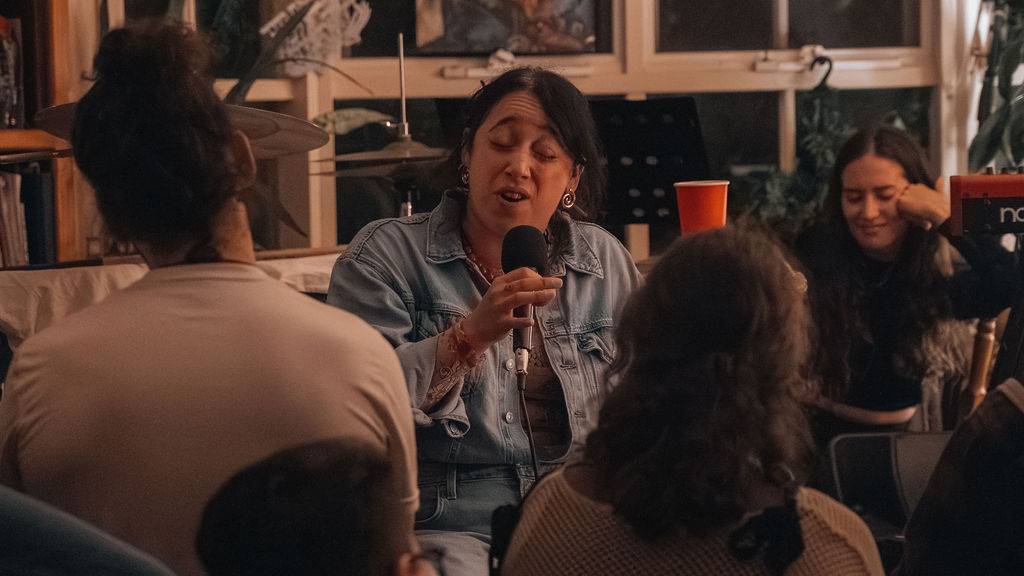 a performer singing into a handheld mic, audience close by